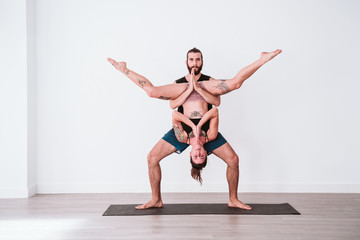 young couple Couple practicing acro yoga in white studio or gym. Healthy lifestyle