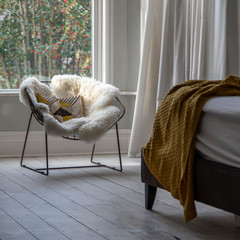 Modern armchair covered in soft furnishings in a bright bedroom