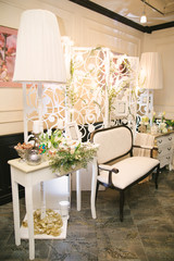 Photo zone wedding. Carved white panel and classic sofa, decorative lamps