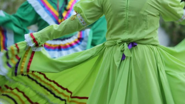 close up of a two mexican female dancers waving their colorful mexican folk dresses, mariachi music