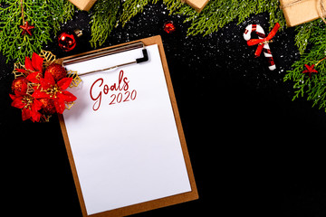 Christmas composition. Girlanda with Christmas ornaments and gifts on black background and blank notepad. Christmas, winter, new year concept. Goals 2020 © Julio Ricco