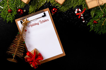 Christmas composition. Girlanda with Christmas ornaments and gifts on black background and blank notepad. Christmas, winter, new year concept.. Holiday Wishes © Julio Ricco