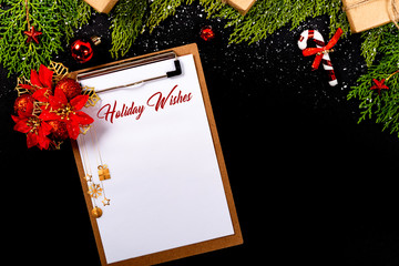 Christmas composition. Girlanda with Christmas ornaments and gifts on black background and blank notepad. Christmas, winter, new year concept. Holiday Wishes © Julio Ricco