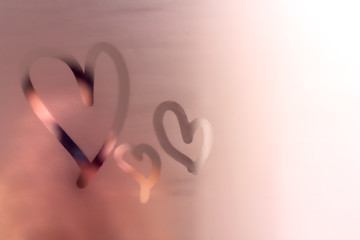 Three abstract hearts painted on fogged bathroom mirror. Finger drawing on glass. Romantic love...