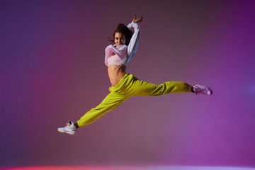 Beautiful cheerful girl jumping doing split leap in the air, looking straight at camera with joyful expression, flexible and weightless concept professional dancer in motion