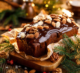 Gingerbread cake, Christmas gingerbread cake covered with chocolate and decorated with nuts and almonds on the holiday table. Christmas, traditional dessert - obrazy, fototapety, plakaty