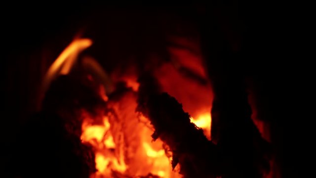 A stead focus pull shot of flames burning wood leaving hot coals and embers
