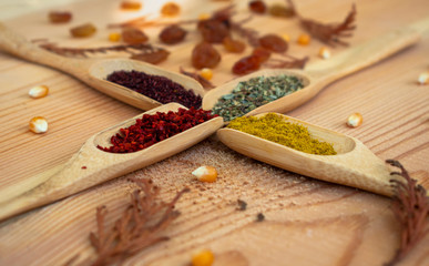 different kinds of spices, wooden spoons and copy space on wooden background