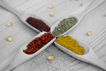different kinds of spices, wooden spoons and copy space on wooden background
