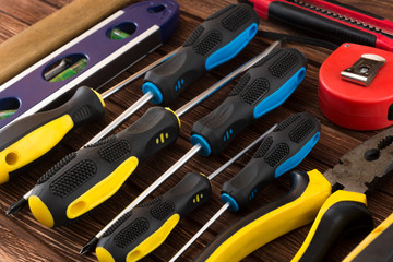 Work tool of the wizard. Screwdrivers, pliers, wire cutters, building level, tape measure, hammer, wrenches, square and other tools on a wooden surface. Free space for text.