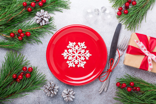 Christmas table place setting with empty red plate, cutlery with festive decorations star bow ball deer on stone background. Christmas and New Year holiday concept - Image