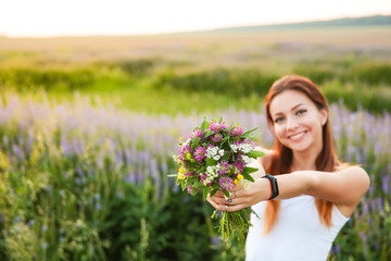 Naklejka na ściany i meble carefree girl is enjoying by bouquet of wildflowers in the wild flowers field