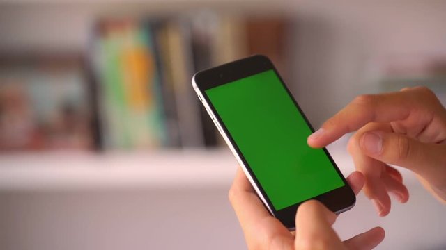 girl hands scroll on phone green chroma key image with colourful blurry books in background slow motion closeup