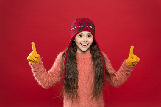 Look here. Little girl winter fashion accessory. Small child wear hat burgundy background. Cute model enjoy winter style. Presentation concept. Winter outfit. Little kid wear knitted hat. Stay warm