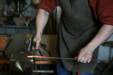 blacksmith knocks a hammer on the hot metal on the anvil. the work of a blacksmith in the forge