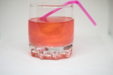 Pink drink in a glass cup with a pink straw for cocktails isolated on white background