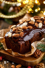 Christmas gingerbread cake,  gingerbread cake covered with chocolate and decorated with nuts and almonds on the holiday table, close-up. Christmas, traditional dessert