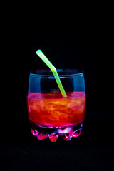 Glitter drink with a cocktail tube close-up isolated on a black background