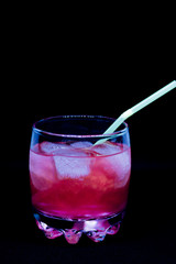 Glitter drink with a cocktail tube close-up isolated on a black background