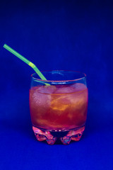 Orange drink with glitter and straw isolated close-up on a blue background