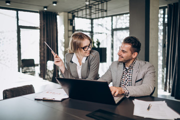 Coworking white collar colleagues smiling to each other as they reach success