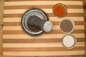 Spices red ground pepper, black ground pepper, salt, peas and peas in a pepper mill on a wooden...
