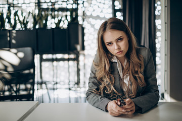 Portrait of serious thoughtful young business woman looking at camera with her head slightly bent forward