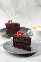 A slice of delicious chocolate cake with cherry on top on marble background. Piece of Cake on a Plate. Sweet food. Sweet dessert. Close up. Cafe menu. vertical photo.