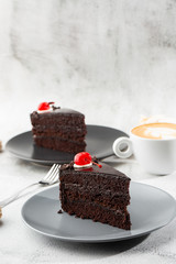 A slice of delicious chocolate cake with cherry on top on marble background. Piece of Cake on a Plate. Sweet food. Sweet dessert. Close up. Cafe menu. vertical photo.