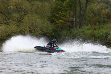 man in a helmet and wetsuit performs tricks on a jet ski. sport riding a personal watercraft. stunt...
