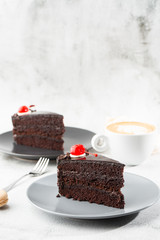 A slice of delicious chocolate cake with cherry on top on marble background. Piece of Cake on a Plate. Sweet food. Sweet dessert. Close up. Cafe menu. vertical photo.