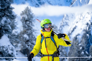 Fototapeta na wymiar Portrait of sportive man in helmet with skis on his shoulder