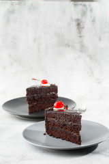 A slice of delicious chocolate cake with cherry on top on marble background. Piece of Cake on a Plate. Sweet food. Sweet dessert. Close up. Cafe menu. vertical photo.