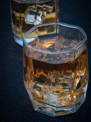 Two glasses of whiskey with ice on a black background - 302063674