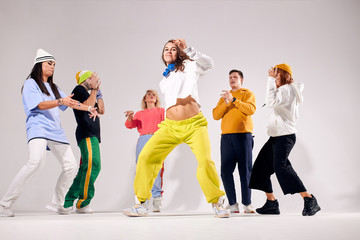 Young pretty girl showing perfect dance element, moving quickly, showing emotions, friends standing behind with impression, dancers of soul hip hop, funk, house dance