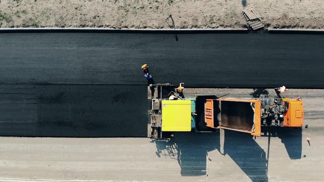 Top view of road makers spreading asphalt