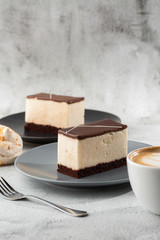Piece of cake with souffle Bird's milk , biscuit, mousse and dark chocolate on a dark plate, white...
