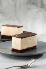 Piece of cake with souffle Bird's milk , biscuit, mousse and dark chocolate on a dark plate, white souffle cake. Menu for bakery. cafe menu. Delicious and sweet dessert at cafe restaurant.Vertical
