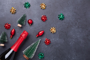 Christmas composition with champagne and red, green, gold gifts and bows on dark stone background. Christmas and New Year holiday concept - Image