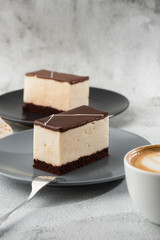Piece of cake with souffle Bird's milk , biscuit, mousse and dark chocolate on a dark plate, white...