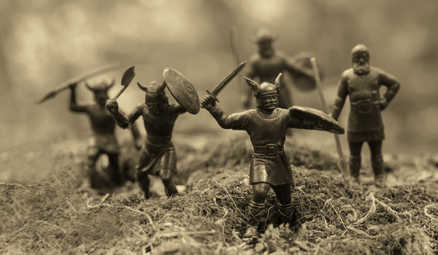 Five well armed attacking Vikings (toy soldiers), located on a mossy place, misty blurred background, selective focus, Old Norse Gods, Valhalla topic, epic myths, monochrome photo (sepia)