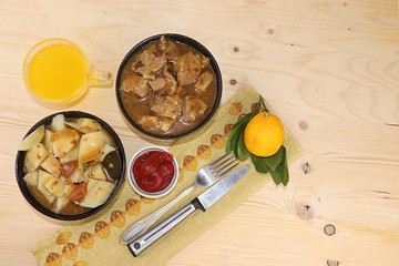 Meat goulash in a dark cup, stewed potato stew and a mug with lemon juice, the basis of diet food,...