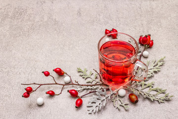 Hot dog-rose tea. Winter drink for good mood with fresh berries, leaves and candies. Stone concrete...