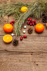 Fototapeta na wymiar Spirit Christmas background. Fresh mandarins, dog-rose berries, candies, pine branches and cones, artificial snow