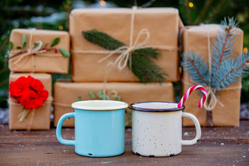 Two cups of coffee with boxes and fairy lights and pine tree on background