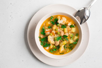 Homemade Italian minestrone - rustic vegetarian soup made with: beans, cauliflowers, onion, celery, carrots, tomatoes, potatoes, zucchini.