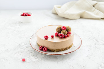 Raw cocoa cake garnished with energy balls and raspberries. Gluten free.
