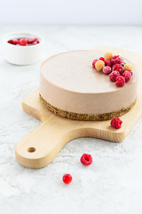 Raw chocolate cheesecake with raspberries on a wooden board. Gluten free, vegetarian food.