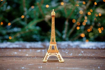 Fotobehang Golden eiffel tower souvenir on table with spruce on background © Masson
