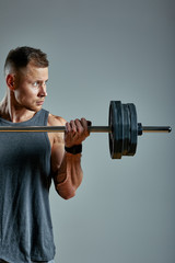 Man doing back workout, barbell row in studio over gray background. Copy space